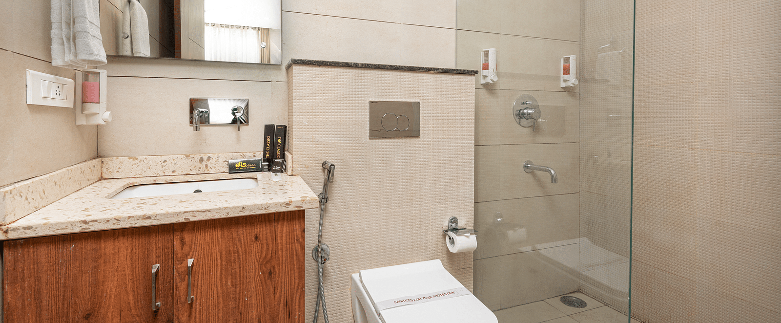 A deluxe room washroom featuring a large mirror and neatly arranged toiletries at DLS The Classio